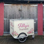 Four-wheeled ice cream cart with a front freezer box and colourful branding, designed for mobile ice cream vending at events and street locations.